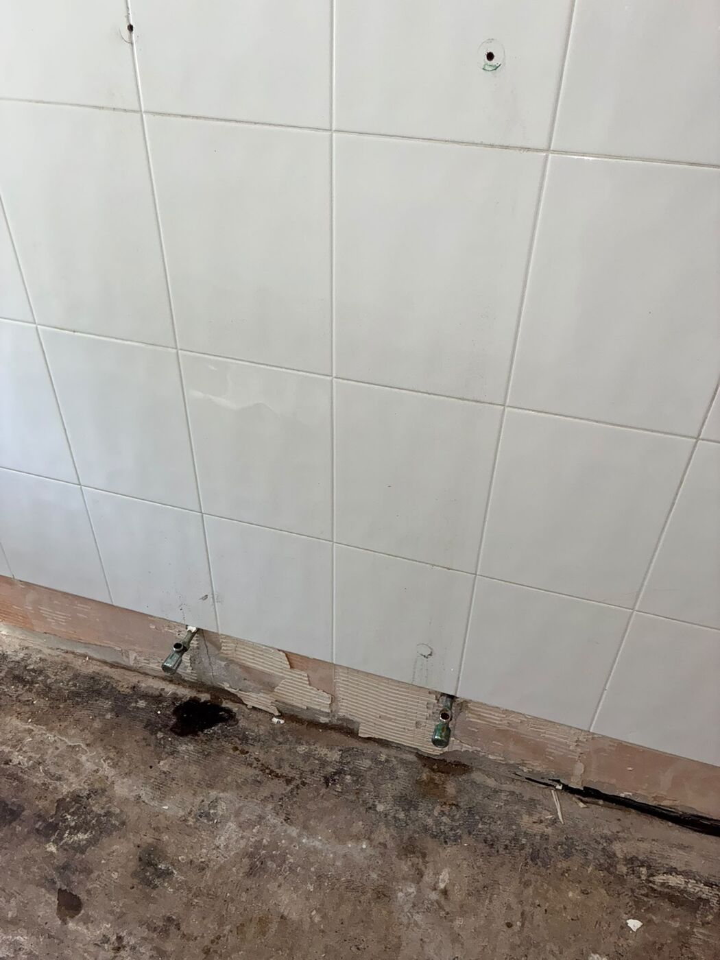 Bathroom stripped back to bare walls and floor with pipe work exposed