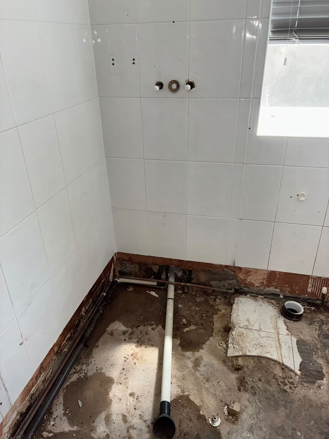 Bare bathroom with capped pipe stubs ready for first fix pipe work