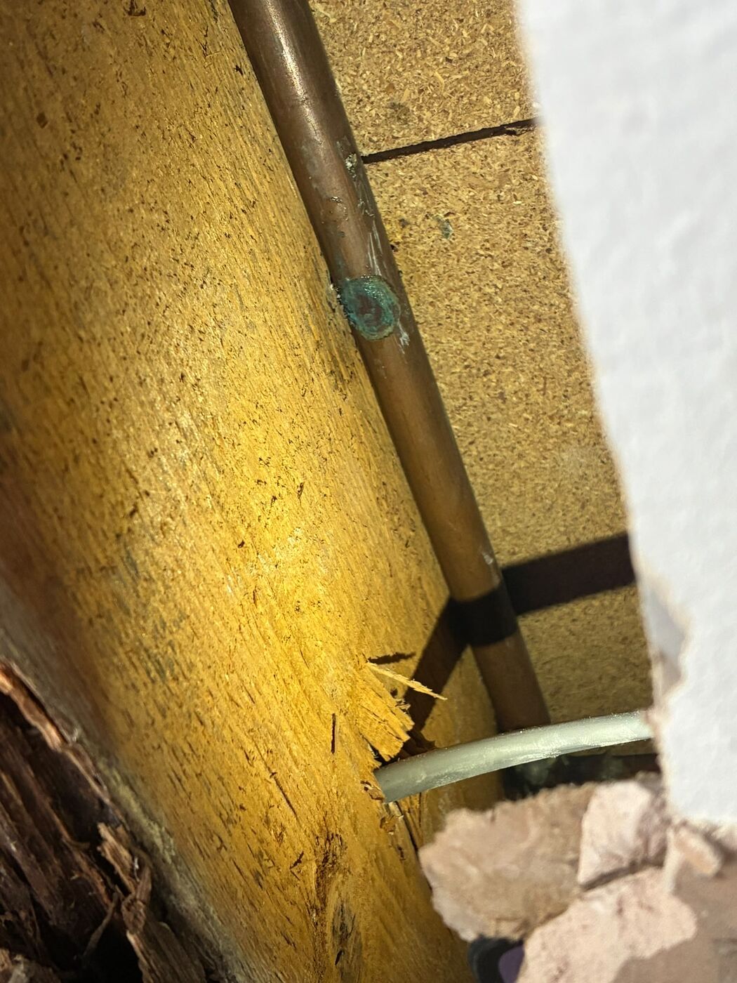 Copper pipe run exposed behind a wall board while tracing a leak