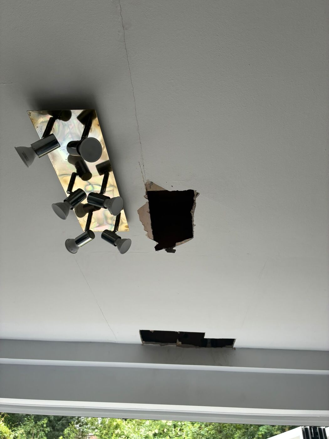 Repaired pipe joints visible through two neat access openings in a ceiling