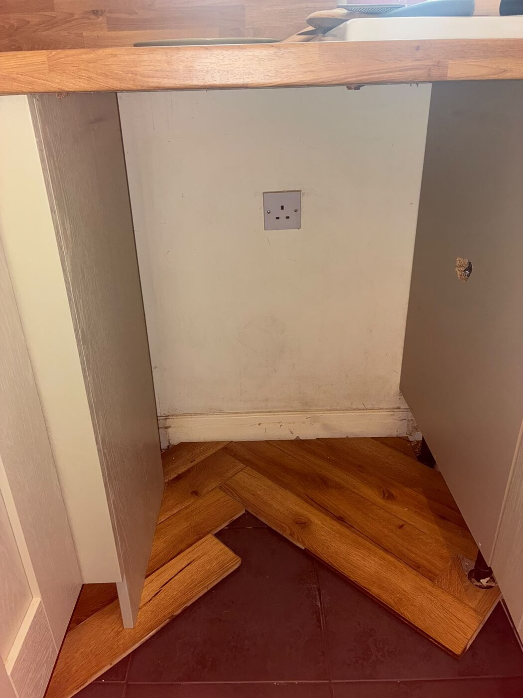 Empty kitchen alcove with wooden worktop after appliance removal and capping off